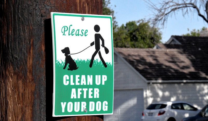 Schild: Bitte räumen Sie die Hinterlassenschaften Ihres Hundes auf. 